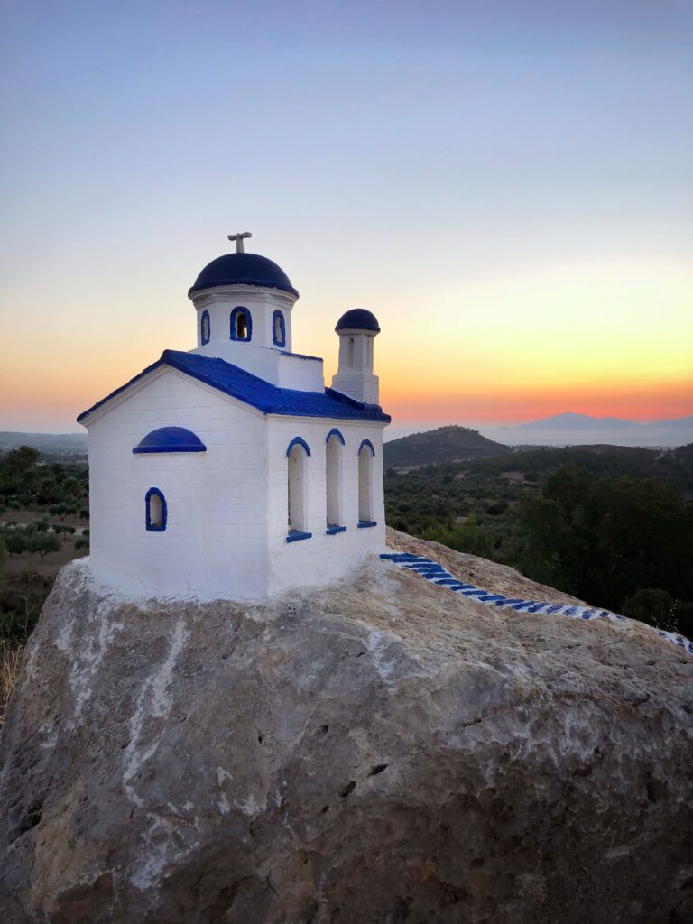 Blue and white chapel on Kastri Island at sunset near Agios Stefanos