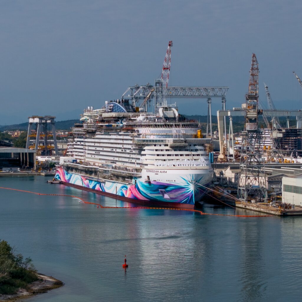 Three-quarter view of Norwegian Aura showing its bow and colourful hull artwork during construction