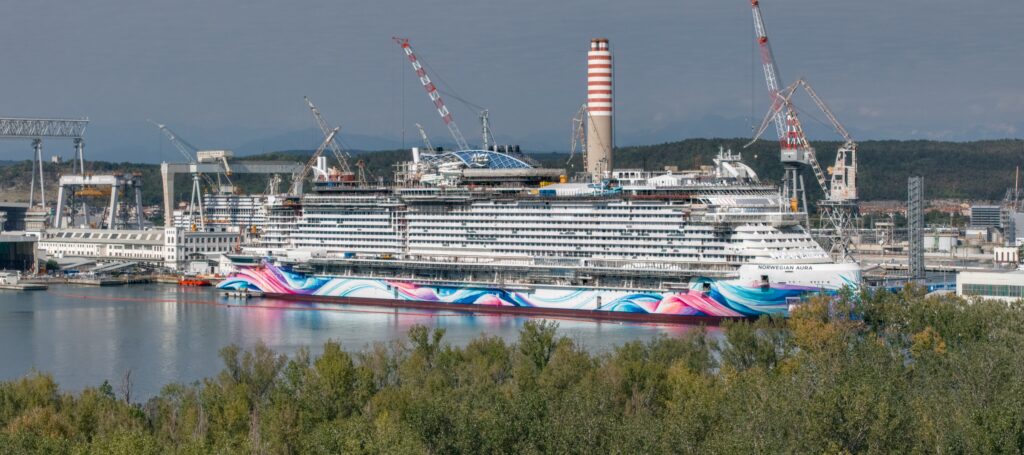 Norwegian Aura surrounded by cranes at Fincantieri shipyard in Monfalcone, Italy
